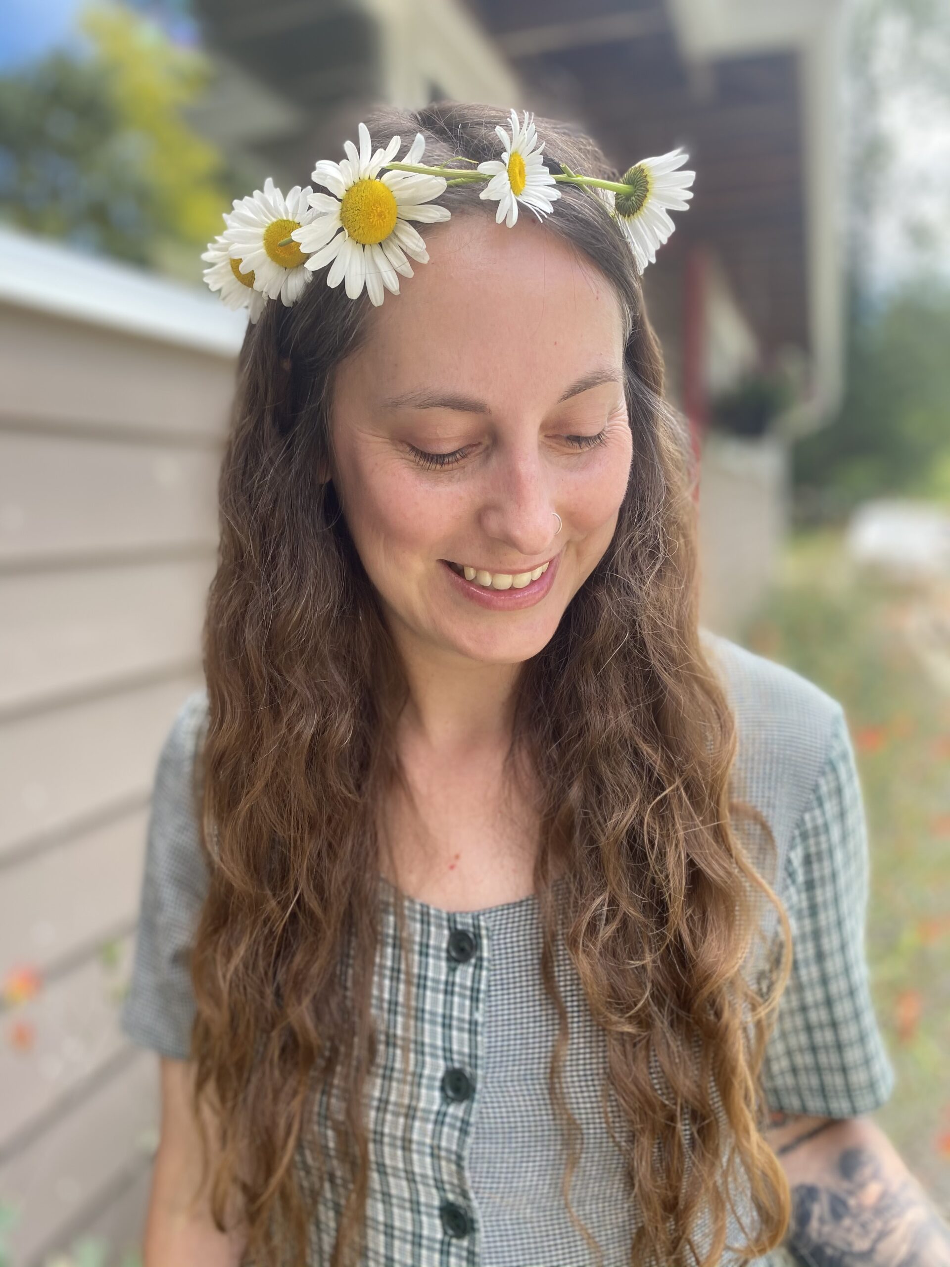 Photo of Madeline Christie, woman with long wavy hair and a crown of daisies on her head